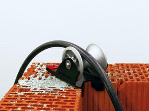 RUNPOTEC Grey and Black Cable Guide Roller – Shaft Inside Edge in use attached to corner of a brick wall rolling black cable